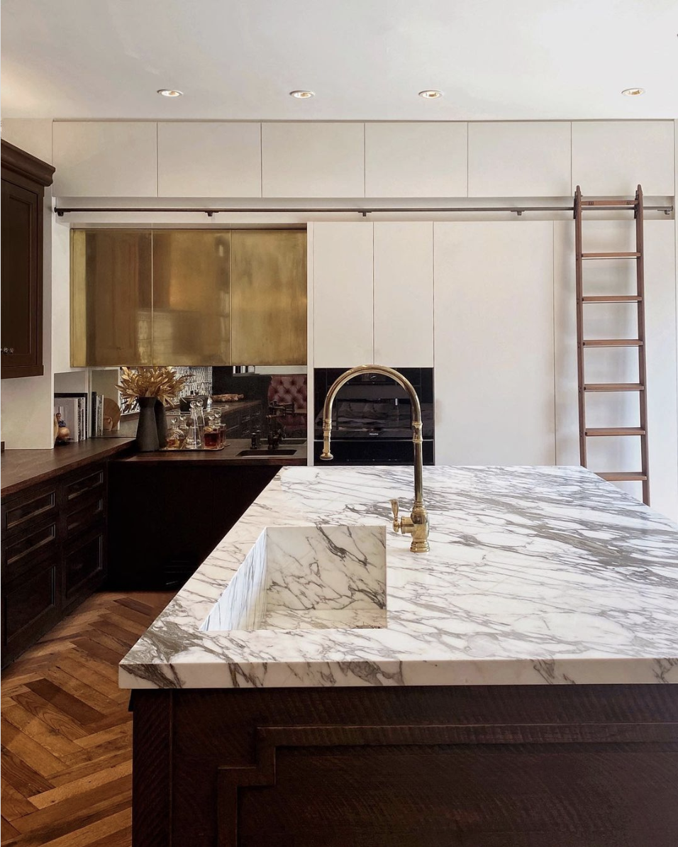 The classic elegance of marble is complemented perfectly by the warm patina of unlacquered brass, creating a kitchen that is both timeless and modern.